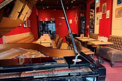 Terrasse vide d'un café avec des chaises alignées, devant une façade en pierre dans une rue pavée.