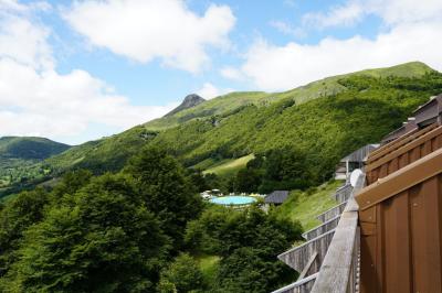 Salle de restaurant lumineuse avec poutres apparentes, grandes fenêtres, tables en bois et chaises hautes.
