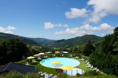 Salle de restaurant lumineuse avec poutres apparentes, grandes fenêtres, tables en bois et chaises hautes.