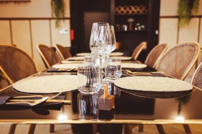 Salle de restaurant chaleureuse avec des tables dressées, une cave à vin visible et un serveur en action.