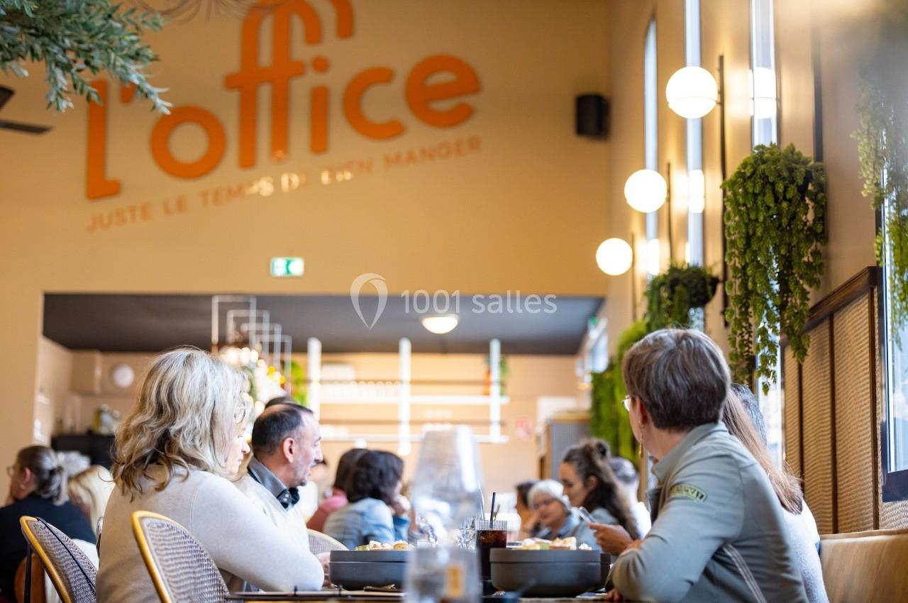 Des personnes assises à des tables dans un restaurant lumineux avec des plantes et une enseigne murale visible en arrière…