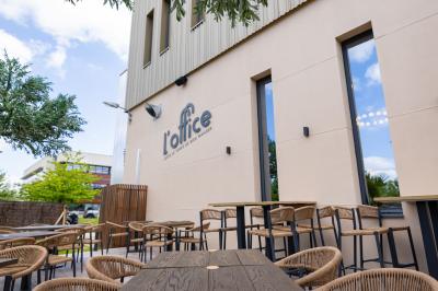 Salle de restaurant chaleureuse avec des tables dressées, une cave à vin visible et un serveur en action.
