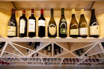 Salle de restaurant chaleureuse avec des tables dressées, une cave à vin visible et un serveur en action.