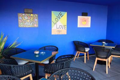 Salle de restaurant chaleureuse avec des tables dressées, une cave à vin visible et un serveur en action.
