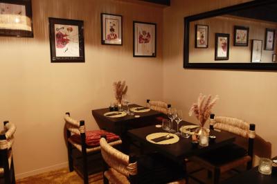 Salle de restaurant chaleureuse avec des tables dressées, une cave à vin visible et un serveur en action.