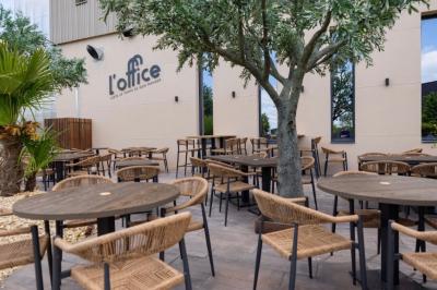 Salle de restaurant chaleureuse avec des tables dressées, une cave à vin visible et un serveur en action.