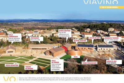 Salle de réunion lumineuse avec tables en U, chaises en bois, tonneau décoratif et étagères murales garnies de bouteilles.