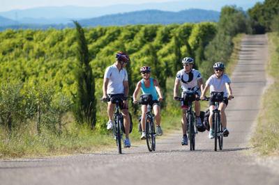 Salle de réunion lumineuse avec tables en U, chaises en bois, tonneau décoratif et étagères murales garnies de bouteilles.