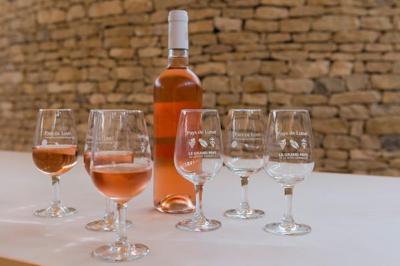 Salle de réunion lumineuse avec tables en U, chaises en bois, tonneau décoratif et étagères murales garnies de bouteilles.
