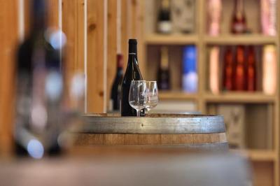 Salle de réunion lumineuse avec tables en U, chaises en bois, tonneau décoratif et étagères murales garnies de bouteilles.