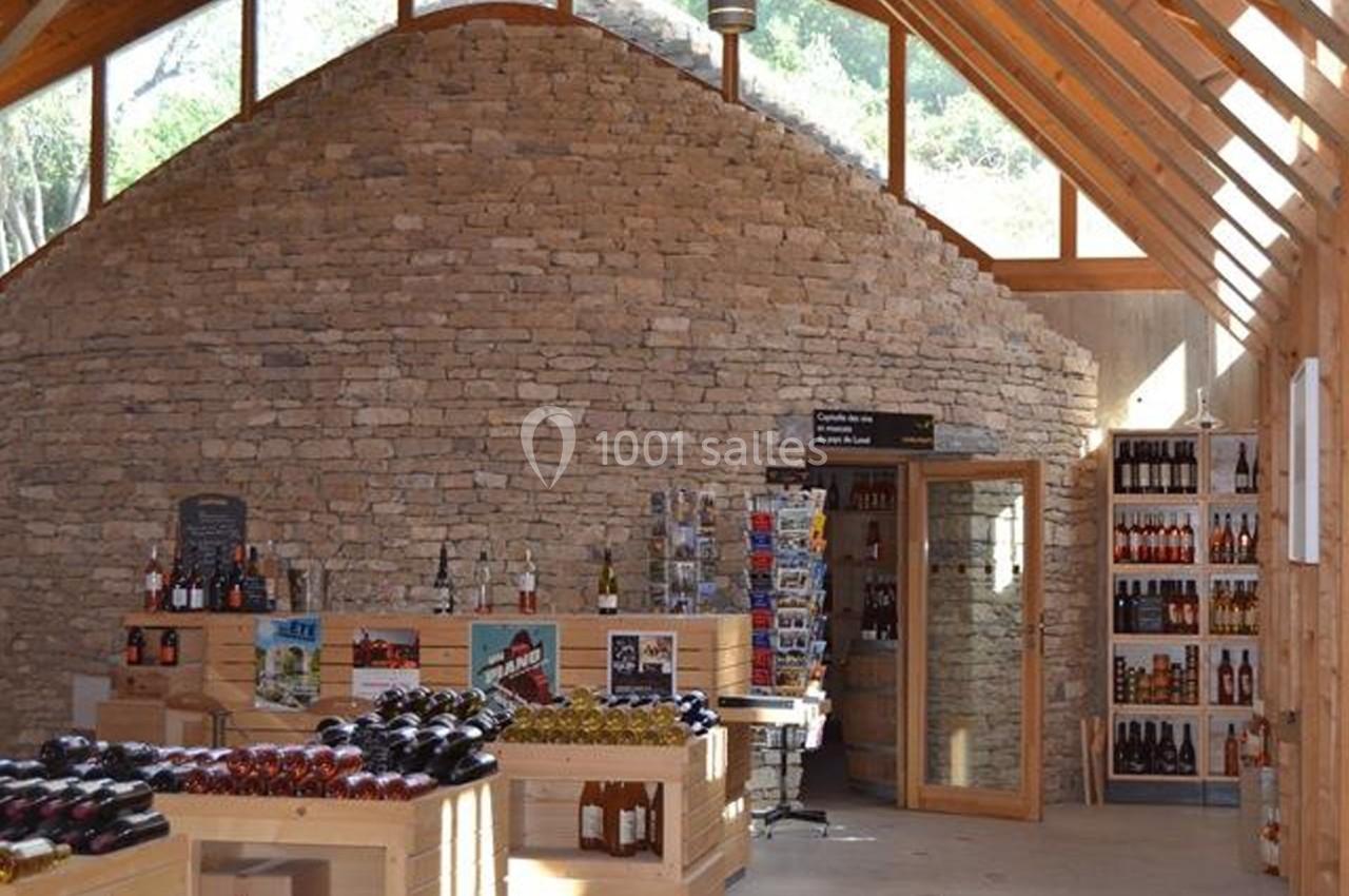 Intérieur d'une boutique avec des étagères en bois exposant des bouteilles et un mur en pierre au fond.