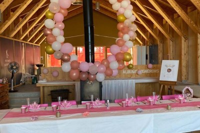 Salle de réunion lumineuse avec tables en U, chaises en bois, tonneau décoratif et étagères murales garnies de bouteilles.