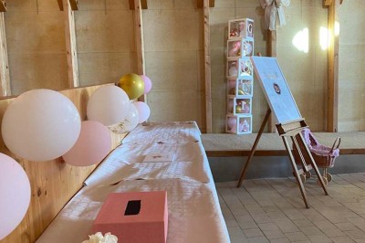 Salle de réunion lumineuse avec tables en U, chaises en bois, tonneau décoratif et étagères murales garnies de bouteilles.