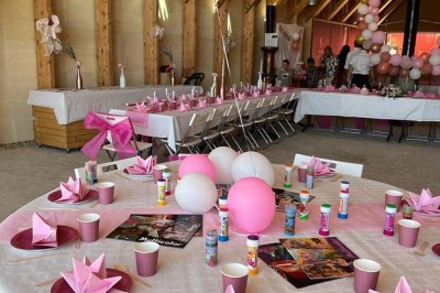 Salle de réunion lumineuse avec tables en U, chaises en bois, tonneau décoratif et étagères murales garnies de bouteilles.