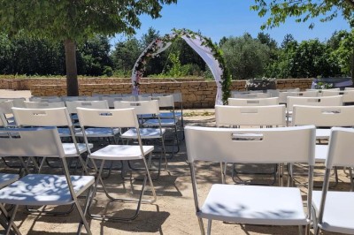 Salle de réunion lumineuse avec tables en U, chaises en bois, tonneau décoratif et étagères murales garnies de bouteilles.
