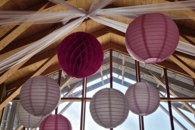 Salle de réunion lumineuse avec tables en U, chaises en bois, tonneau décoratif et étagères murales garnies de bouteilles.