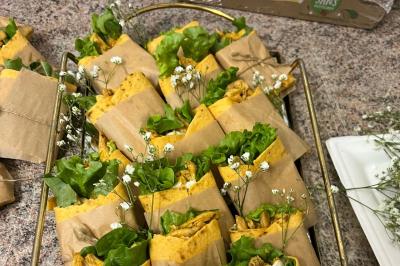 Macaron rouge garni de crème, framboise et groseilles, présenté sur une assiette blanche avec une cuillère dorée.