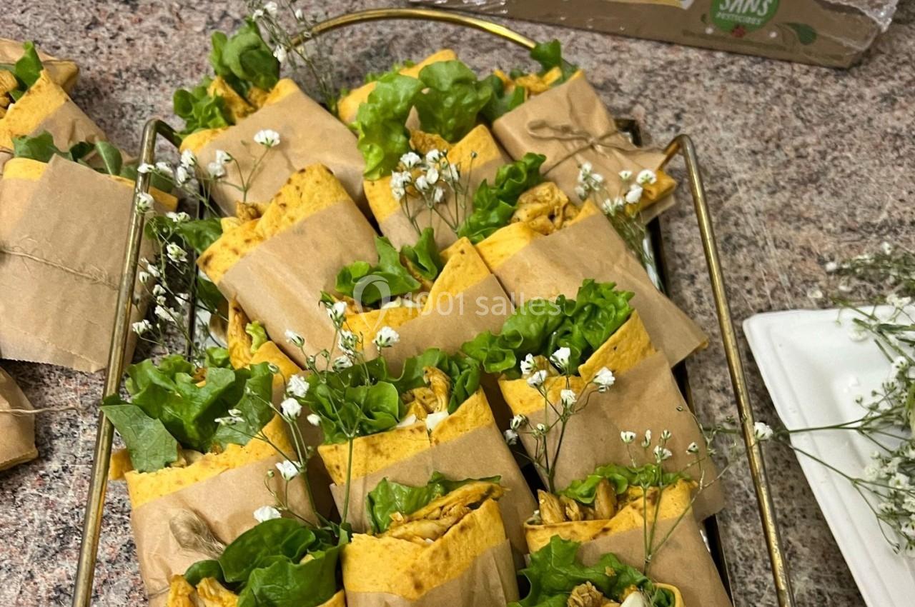 Wraps garnis de salade verte et de morceaux de poulet, présentés dans un papier kraft avec une décoration florale.