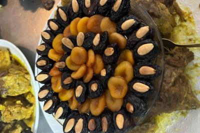 Macaron rouge garni de crème, framboise et groseilles, présenté sur une assiette blanche avec une cuillère dorée.