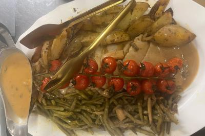 Macaron rouge garni de crème, framboise et groseilles, présenté sur une assiette blanche avec une cuillère dorée.