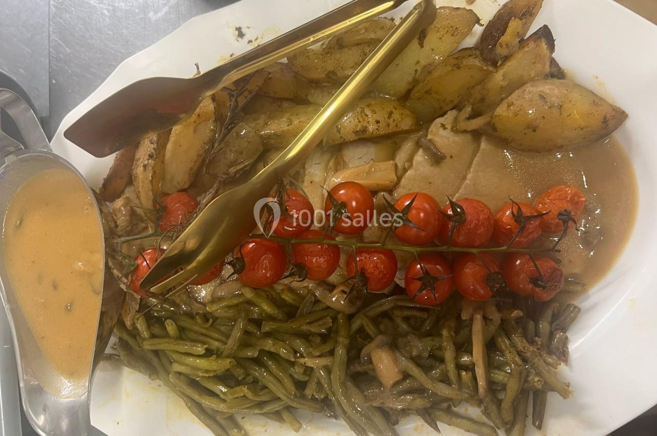 Assiette contenant rôti de viande, pommes de terre rôties, haricots verts, tomates cerises grillées et sauce servie à part.