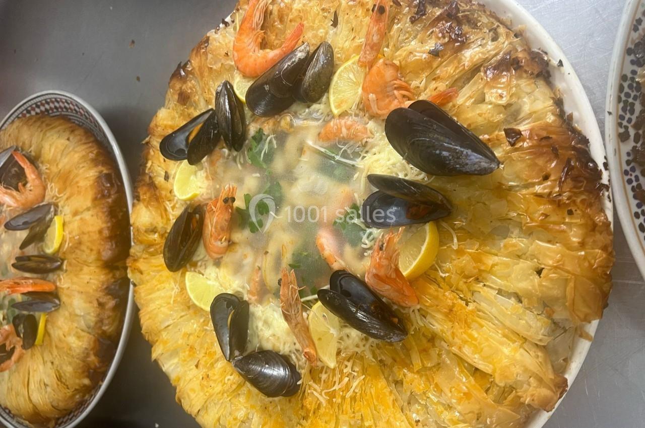 Plat de fruits de mer avec crevettes, moules et citron, présenté sur une pâte croustillante en forme de couronne.
