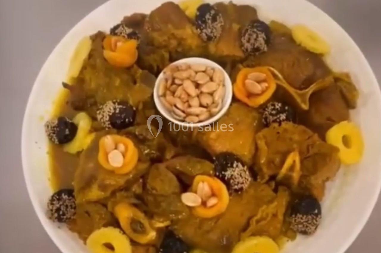 Plat de viande en sauce avec pruneaux, abricots secs, amandes et rondelles d'ananas, présenté dans une assiette blanche.