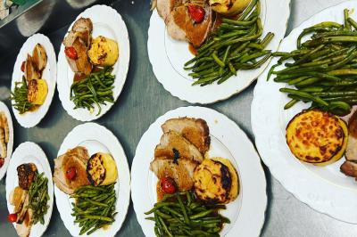 Macaron rouge garni de crème, framboise et groseilles, présenté sur une assiette blanche avec une cuillère dorée.