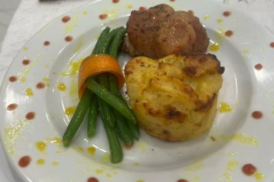 Macaron rouge garni de crème, framboise et groseilles, présenté sur une assiette blanche avec une cuillère dorée.