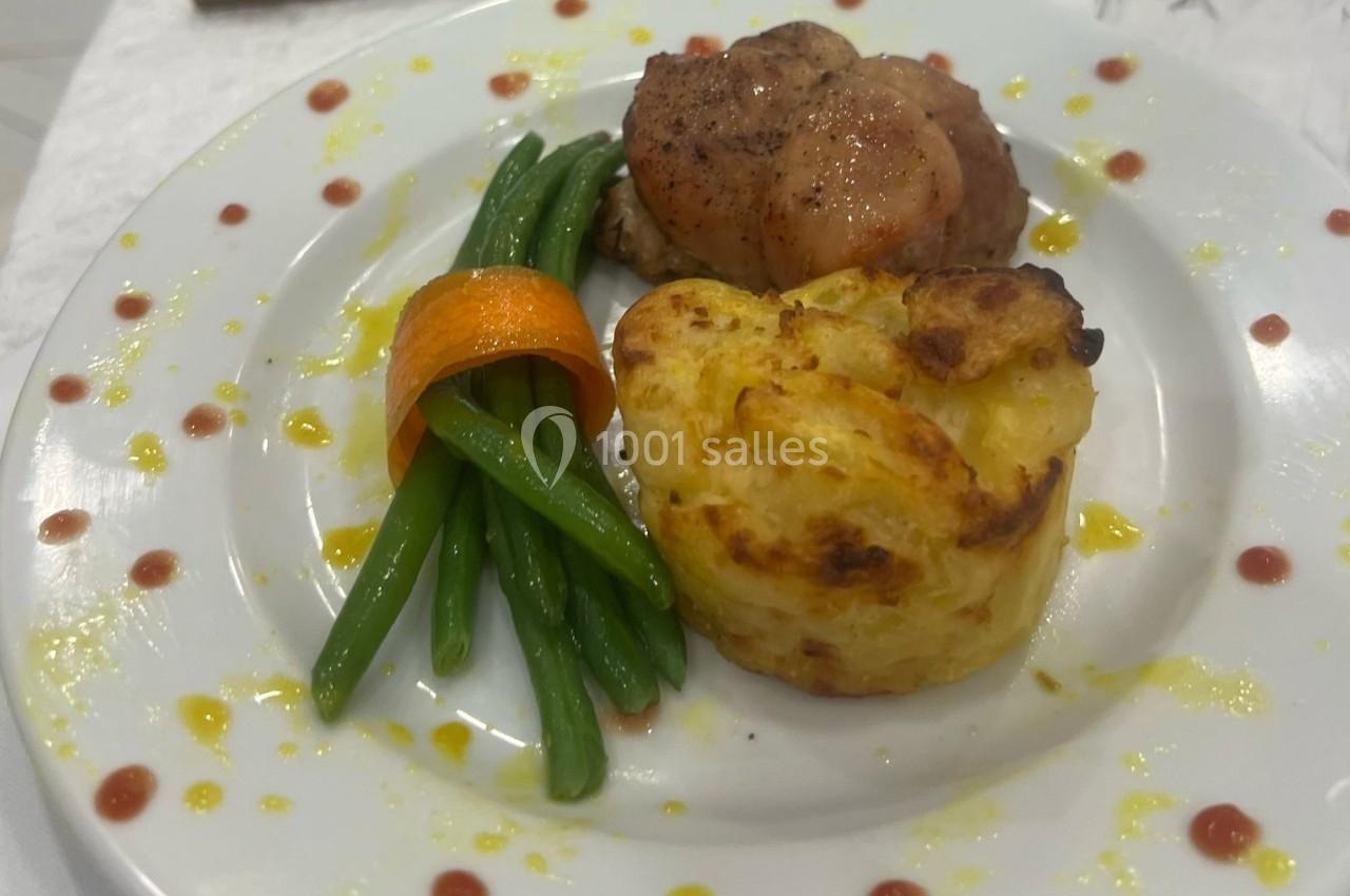 Assiette avec filet de viande, haricots verts, ruban de carotte et gratin de pommes de terre, décorée de sauce.