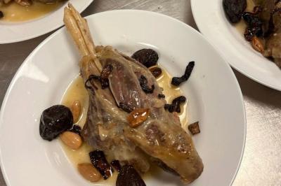 Macaron rouge garni de crème, framboise et groseilles, présenté sur une assiette blanche avec une cuillère dorée.