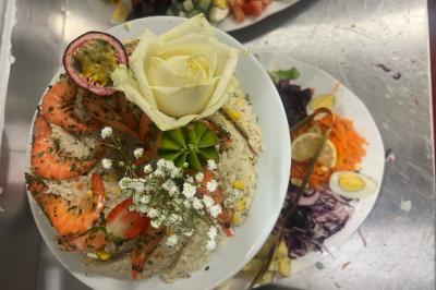 Macaron rouge garni de crème, framboise et groseilles, présenté sur une assiette blanche avec une cuillère dorée.