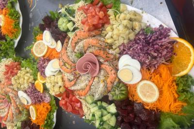 Macaron rouge garni de crème, framboise et groseilles, présenté sur une assiette blanche avec une cuillère dorée.