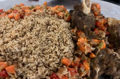 Macaron rouge garni de crème, framboise et groseilles, présenté sur une assiette blanche avec une cuillère dorée.