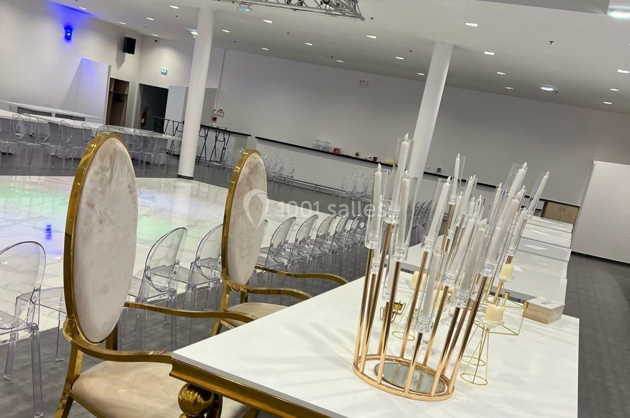 Salle de réception moderne avec chaises transparentes, grandes chaises dorées et décoration en bougeoirs design.