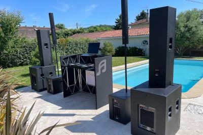 Système de sonorisation installé en extérieur près d'une piscine, avec une table de mixage et des enceintes.