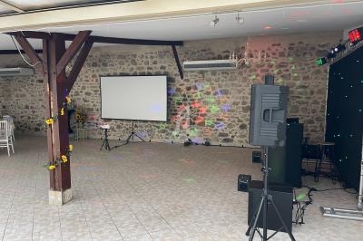 Salle avec murs en pierre, écran de projection, éclairage coloré et équipement audio, décorée de tournesols.
