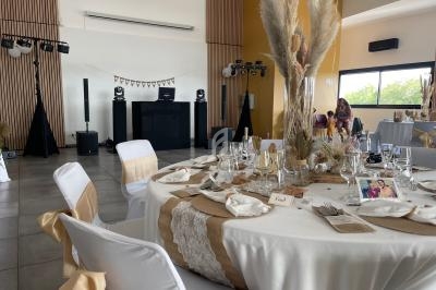 Salle de réception décorée dans des tons neutres avec une table dressée et des éléments de décoration en pampas.