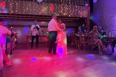 Un couple danse au centre d'une salle décorée de guirlandes lumineuses, entouré d'invités assis.