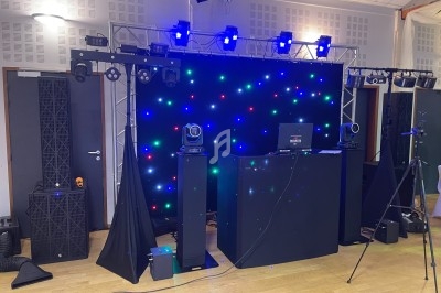 Installation de matériel de sonorisation et d'éclairage avec projecteurs, enceintes et fond lumineux multicolore.