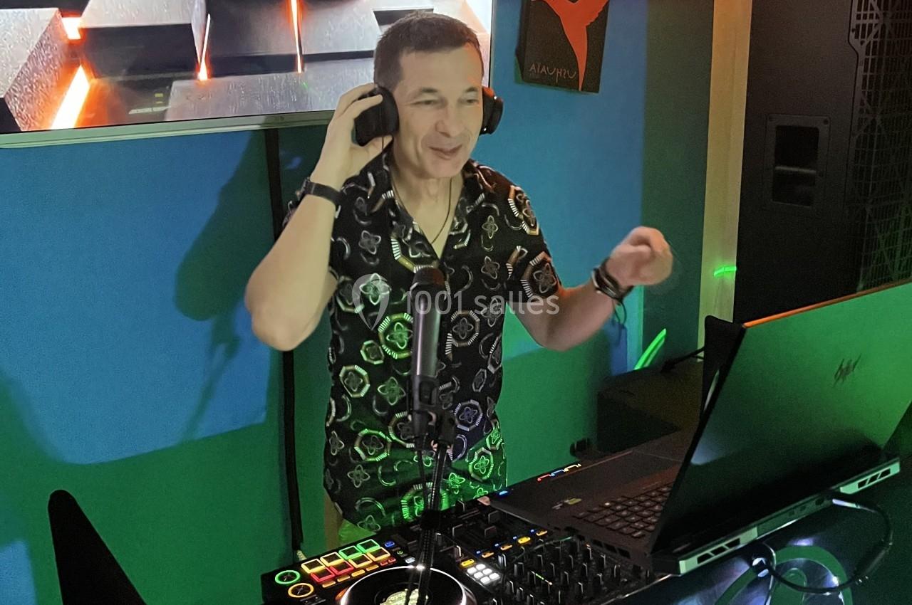 Un DJ souriant mixe de la musique sur une console dans un environnement lumineux et coloré.