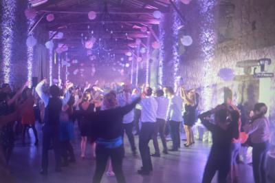 Groupe de personnes dans une salle en pierre éclairée, dansant sous des décorations suspendues.