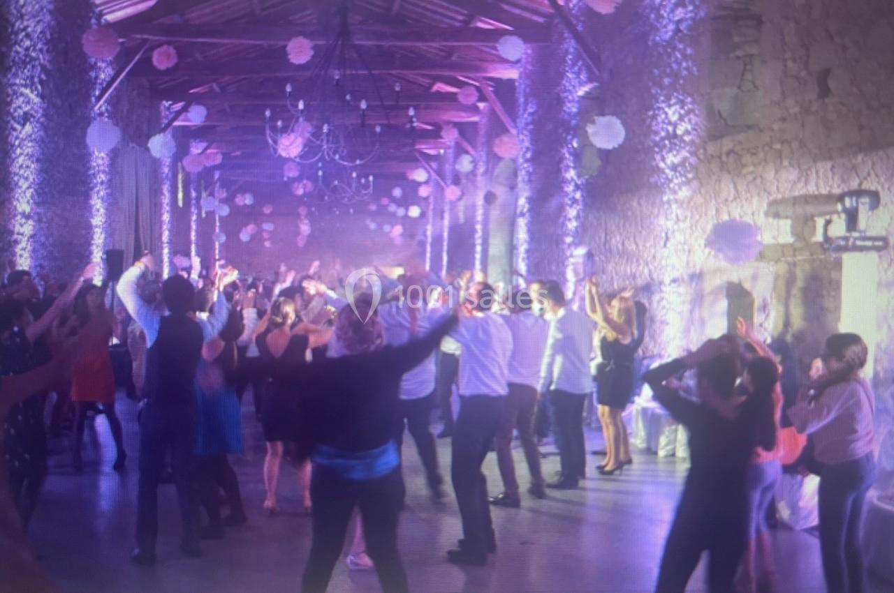 Groupe de personnes dans une salle en pierre éclairée, dansant sous des décorations suspendues.