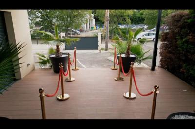Terrasse avec piscine, transats blancs, parasols fermés et un bar en arrière-plan sous un ciel dégagé.