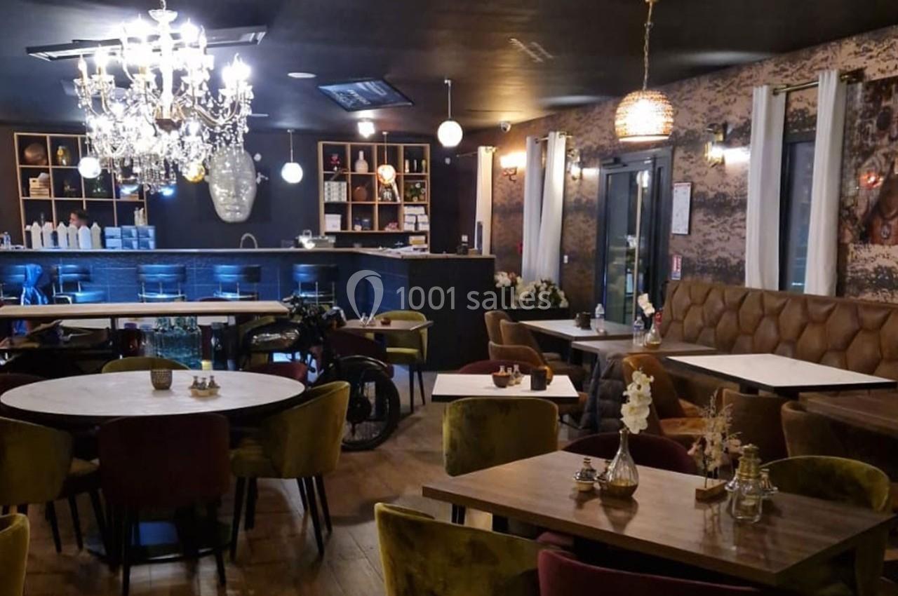 Salle de restaurant élégante avec tables en bois, chaises colorées, lustres et éclairage tamisé.