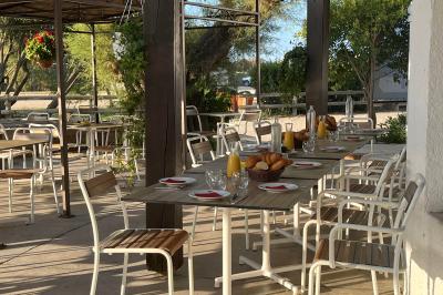 Tables élégamment dressées avec nappes blanches, serviettes pliées, verres et décorations florales dans une salle lumineuse.
