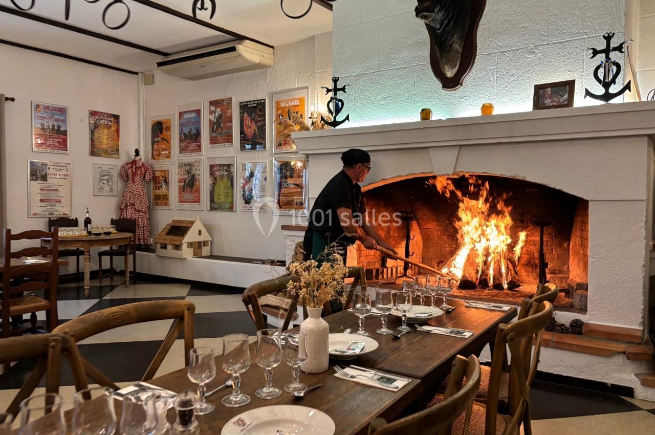 Un homme alimente un feu de cheminée dans un restaurant décoré de photos et d'objets traditionnels.