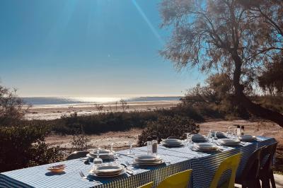 Tables élégamment dressées avec nappes blanches, serviettes pliées, verres et décorations florales dans une salle lumineuse.