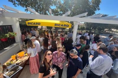 Tables élégamment dressées avec nappes blanches, serviettes pliées, verres et décorations florales dans une salle lumineuse.