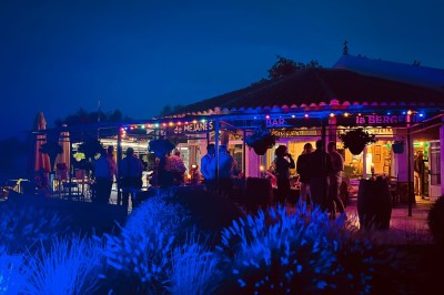 Tables élégamment dressées avec nappes blanches, serviettes pliées, verres et décorations florales dans une salle lumineuse.